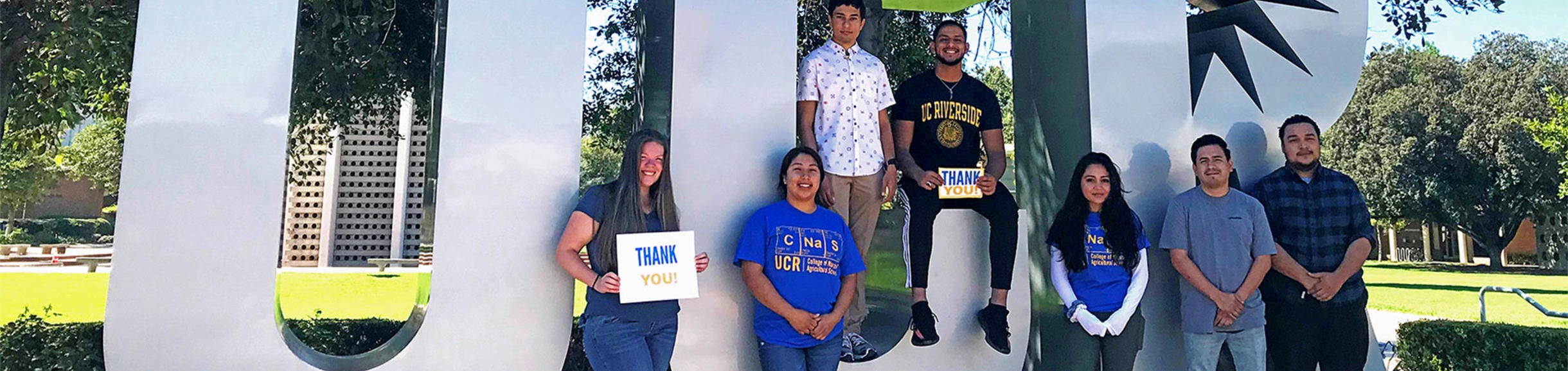 students in front of UCR sign holding thank you signs