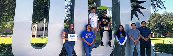 students in front of UCR sign holding thank you signs